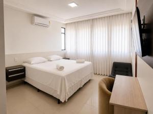 a bedroom with a white bed and a chair at Hotel Residence in Caruaru