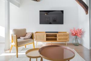 a living room with a table and chairs and a tv at Le Grand Rue Signature - Appartement coeur de ville, rue piétonne in Bergerac