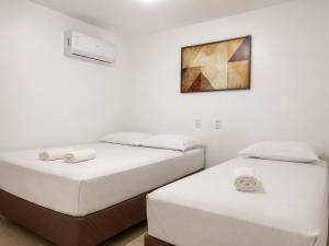 two twin beds in a room with a painting on the wall at Hotel Residence in Caruaru