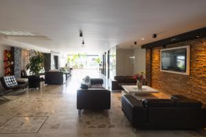Ein Wohnzimmer mit Sofas und einem Fernseher an einer Backsteinwand in der Unterkunft Hotel Alessio in Bucaramanga