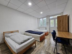 two beds in a room with a desk and windows at JOPEL ubytovanie v súkromí in Slovenské ďrmoty
