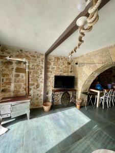 a living room with a tv and a stone wall at Ahiri traditional cottage in Galatás