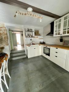 a kitchen with white cabinets and a table and a staircase at Ahiri traditional cottage in Galatás
