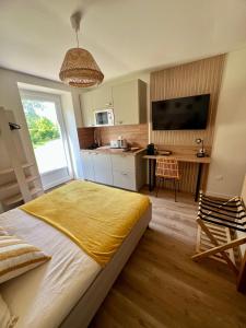 a bedroom with a large bed and a kitchen at L'Escale d'Armorique 1 in Languidic