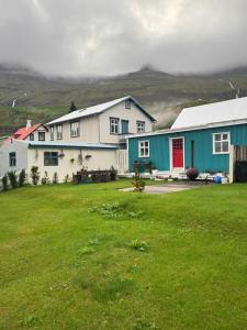a group of houses with a grass field in front at Nýlenda - Charming Two Bedroom Seaside Property, Mountain and Town Views in Seyðisfjörður