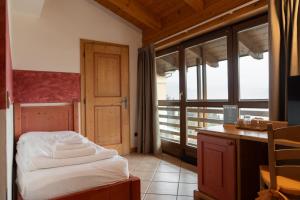 a bedroom with a bed and a desk and a window at Hotel al Dòs - Breakfast & Private SPA in Trento