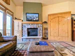 a living room with a stone fireplace and a tv at Arapahoe Lodge 8105 by SummitCove Lodging in Colorado in Keystone
