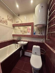 a bathroom with a toilet and a sink and a tub at Central Comfort in Konotop +6 photos
