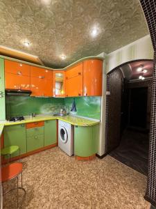 a kitchen with green and orange cabinets and a washing machine at Central Comfort in Konotop