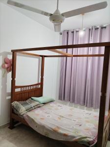 a bedroom with a wooden bed with a ceiling fan at D & N Homes- Villa 1 in Kalutara