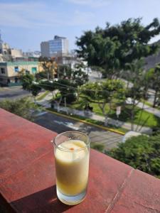 a glass of orange juice sitting on a red table at Casa Huaca in Lima
