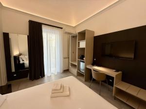 a bedroom with a bed and a desk and a television at Le Quattro Stagioni - Rooms & Suites in Palermo