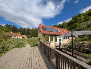a house with a wooden deck and an umbrella at Ferienhaus Grabenhansl in Stubenberg