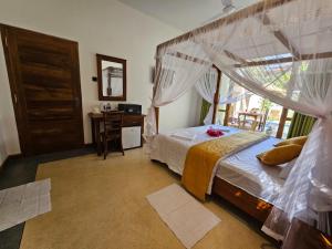 a bedroom with a canopy bed with a desk and a window at The Blacksmith Villa in Habaraduwa Central