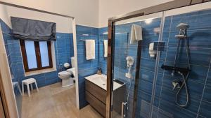 a blue tiled bathroom with a shower and a sink at Janva Guest House in Sciacca