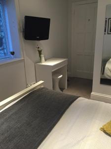 a bedroom with a bed and a desk with a tv on the wall at Copper's Cottage in Sheringham