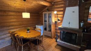a wooden dining room with a table and a fireplace at Midsommar Stuga in Årjäng