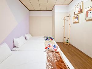 two beds in a room with white walls and wooden floors at Mumian Manlv Homestay in Hengchun South Gate