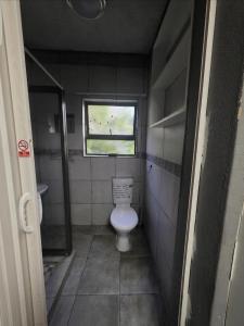 a small bathroom with a toilet and a window at Mgwenya Capsule Hotel in Nelspruit