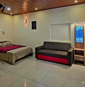 a bedroom with a bed and a couch at Dewdrops Poolvilla in Meppādi