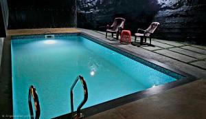 a swimming pool with two chairs at Dewdrops Poolvilla in Meppādi