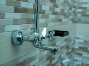 a chrome shower faucet in a bathroom at Umoja Backpacker's Stay in Msaranga +25 photos