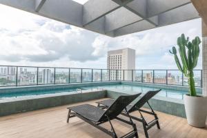 a balcony with a pool and two chairs and a cactus at Full Apartment with Pool and Gym - M1605 in Recife