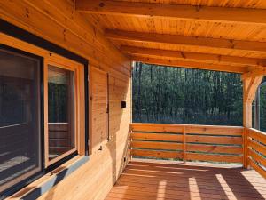 a porch of a wooden cabin with a large window at Cisza Roztocze in Wierzchowiny +2 photos