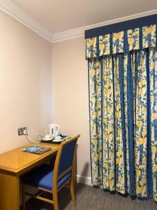 a desk with a blue chair and a curtain at Blaby Westfield Hotel in Blaby +97 photos