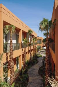 a walkway in front of a building with palm trees at TRIANON Résidence Hôteliere in Marrakesh