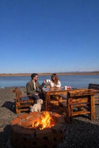 a man and a woman sitting at a table next to a fire at Lake Cottages in Grigoleti +7 photos