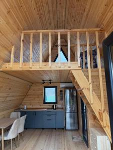 a loft bed in a cabin with a kitchen and a table at Lake Cottages in Grigoleti