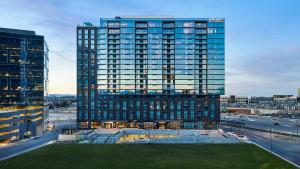 a tall building with a green field in front of it at Apiary Hotel Belleview Station Denver in Denver