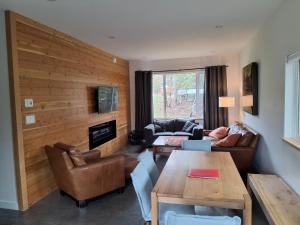 a living room with leather furniture and a wooden wall at Fernie Alpine Retreat in Fernie