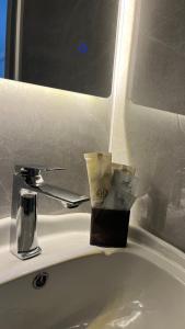 a bathroom sink with a cup on top of it at Эталон АПАРТ-ОТЕЛЬ Aqtobе in Aktobe +42 photos