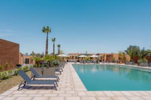 a pool at a resort with lounge chairs and palm trees at TRIANON Résidence Hôteliere in Marrakesh