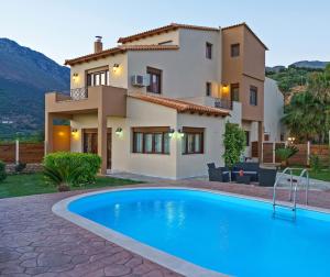a villa with a swimming pool in front of a house at Family Villa Ellis Plakias with private pool 200m to the beach walking distance to the amenities in Plakias
