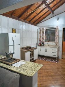 a kitchen with a white refrigerator and a counter at Pousada Vale do Horizonte in Monte Verde