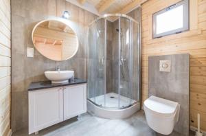 a bathroom with a shower and a sink and a toilet at Domki Między Sosnami in Pobierowo +18 photos
