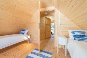 a room with two beds in a wooden cabin at Domki Między Sosnami in Pobierowo