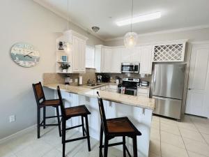 a kitchen with white cabinets and a stainless steel refrigerator at Family Retreat with pool for 6 Pet Lovers 130 E Retama #3 in South Padre Island