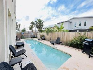 a swimming pool with chairs next to a house at Family Retreat with pool for 6 Pet Lovers 130 E Retama #3 in South Padre Island