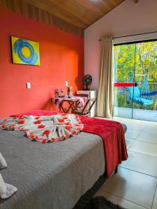 a bedroom with a bed with a red wall at Pousada Vale do Horizonte in Monte Verde