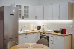 a kitchen with white cabinets and a table and a refrigerator at Datidis Urban Nest in Komotini