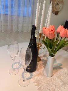 a bottle of wine and two glasses on a table with flowers at Apartman Maja in Prijedor