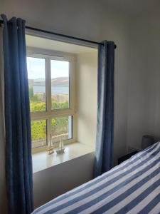 a bedroom with a window with blue curtains and a bed at McGrath's Bar & Accommodation Causeway in Causeway