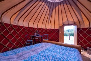 a bedroom in a yurt with a bed and a table at Bunkers Hill Farm in Bramfield
