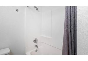 a bathroom with a tub and a shower curtain at Motel 6-Anaheim, CA - Maingate in Anaheim +27 photos