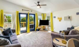 a living room with yellow curtains and a tv at The Rubber Duck in Gravois Mills