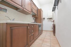 a kitchen with wooden cabinets and a tile floor at Queen Home Funo Centergross in Castel Maggiore